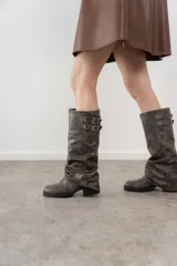 Bota de caña media color negro, con detalle de dos correas con hebillas plateadas en la parte superior.