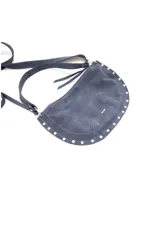 Bandolera azul de gamuza con forma curva, correa ajustable y detalles de tachas plateadas en el borde inferior.