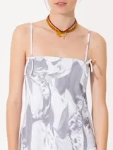 Minivestido blanco con estampado abstracto en gris, breteles finos con moños y corte recto.