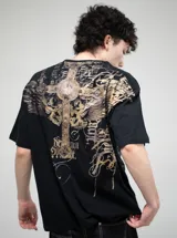 Remera negra de algodón con estampado frontal grande en tonos grises y dorados, con tipografía gótica, un diseño de cruz ornamentada y un felino en el centro.