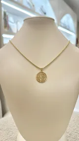 Collar dorado con cadena de eslabones y dije redondo con la imagen de San Benito.