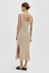 Vestido largo tejido en jersey color beige, con escote redondo y corte con abertura en los laterales.