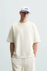 Sudadera relaxed fit color crudo confeccionada en tejido interlock de algodón con elasticidad, cuello redondo, manga corta y bajo acabado en rib.