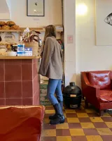 Bota alta de cuero vacuno color negro, con caña recta, puntera cuadrada y detalle de arnés con hebilla metálica plateada.