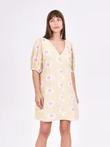 Vestido corto color crema con estampado de soles rosas y blancos, escote en V y mangas abullonadas.