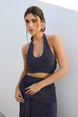 Top corto azul con brillos, escote halter y espalda descubierta.