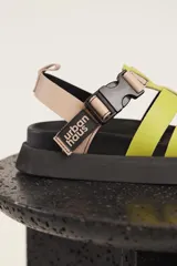 Sandalias Urban Haus con tiras anchas cruzadas color verde lima, ajuste con hebilla y plataforma plana color negro.