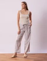 Pantalón largo de lino y rayón a rayas verticales grises y blancas. Tiene pretina elastizada con lazo de ajuste, bolsillos delanteros y traseros.