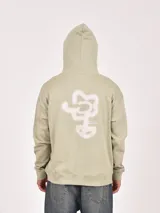 Buzo con capucha color marrón, de tejido liso, con bolsillo canguro frontal y puños y ruedo acanalados. Presenta un pequeño logo circular en la parte inferior del bolsillo.