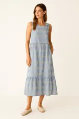 Vestido largo de algodón color celeste con bordado tipo broderie en forma de círculos. Presenta un diseño sin mangas con cuello a la base, corte a la cintura y falda con volado en el ruedo.