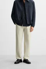 Pantalón chino color beige, corte recto, con bolsillos laterales y traseros. Cierre frontal con cremallera y botón.