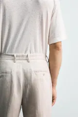 Pantalón de vestir color beige claro, confeccionado en lino, de corte recto, con bolsillos laterales y traseros.