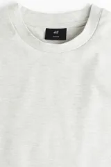 Remera de hombre color gris claro jaspeado, de corte holgado, cuello redondo y manga corta. Confeccionada en tejido de punto de algodón pesado.