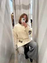 Sweater color crema con cuello alto, mangas largas y corte holgado. Presenta flores bordadas a mano en el puño y tajos laterales.
