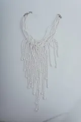 Collar corto con múltiples hilos de cuentas blancas que caen en cascada.