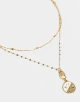 Collar corto dorado de doble cadena, una con bolitas y otra con dije redondo con diseño místico.