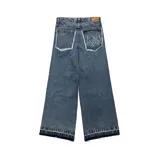 Pantalón jean azul de corte ultra baggy, con bolsillos traseros con diseño de llamas y terminación desflecada.