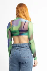 Remera de mangas largas de tul con cuello alto y estampado abstracto en tonos verdes, azules y violetas.