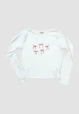 Remera blanca de algodón con cuello redondo y mangas largas. Estampado frontal con diseño de moños rojos.