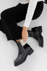 Bota tipo chelsea negra con detalles de tela de corderoy y suela gruesa.