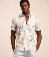 Camisa de hombre confeccionada en voil color crudo con estampa floral estilo outline en azul. Tiene cuello inglés, abotonado delantero y manga corta.