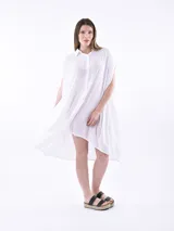 Vestido camisero blanco con corte irregular y mangas cortas.
