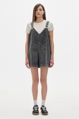 Mono enterito corto de denim color gris oscuro, corte oversized, con tirantes regulables y bolsillo frontal.