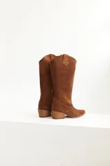 Botas texanas de caña alta color marrón, confeccionadas en gamuza, con puntera fina y taco cuadrado.