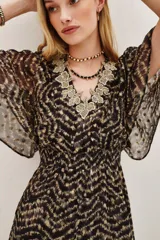 Vestido midi estampado en tonos marrón y beige, con escote en V adornado con bordado floral en tonos dorados/beige. Presenta mangas cortas tipo mariposa y talle ajustado con frunce elástico, falda con abertura frontal.