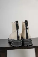 Botas cortas color beige con cierre frontal de cremallera, suela track negra y tirador trasero.