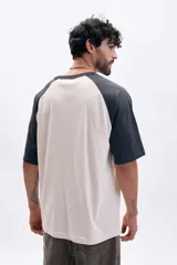 Remera manga corta con mangas ranglan en color gris oscuro y cuerpo color crema.