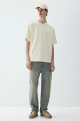 Remera color crema de punto pesado con cuello redondo ribeteado, hombros caídos y bajo recto. Corte holgado confeccionada con tejido funcional Coolmax, una fibra de poliéster de secado rápido que elimina la humedad y regula la temperatura corporal.