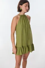 Vestido corto color beige, con escote halter, tirantes finos y falda con volados.