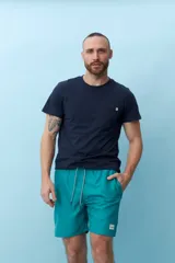 Bermuda de baño color verde agua con cintura elastizada y cordón ajustable. Bolsillos laterales y trasero con etiqueta de marca.