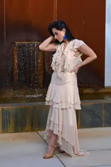 Vestido largo color beige, con escote en V, mangas cortas con volados y falda larga con volados en capas.