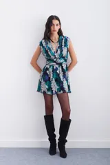Vestido corto con escote en V cruzado con frunces, sin mangas. Confeccionado en viscosa estampada con jacquard en lurex plateado de motivos florales. Con recorte y ajuste en la cintura. Lleva cierre invisible lateral y forrería a tono.