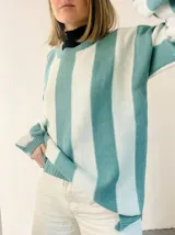 Sweater tejido a rayas horizontales anchas en color celeste y blanco, con sutil brillo. Diseño amplio y cómodo.