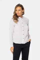 Camisa blanca de lino lisa, de manga larga, con botones metálicos personalizados, dos bolsillos en el pecho y presilla en la manga.