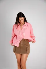 Camisa rosa de manga larga con detalles de encaje en el frente y en las mangas.