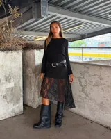 Minifalda negra de encaje con forro, con una capa de encaje más larga y asimétrica que llega hasta la pantorrilla.