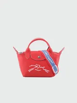 Bolso Longchamp modelo Le Pliage Xtra XS, color rojo con logo de la marca en blanco y correa de tela azul con letras blancas.