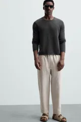 Pantalón negro de lino, corte recto y relaxed fit, con cintura elástica ajustable con cordón, bolsillos laterales y traseros.