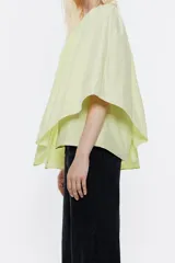 Blusa roja de tafeta con un hombro descubierto, escote recto con volantes y corte holgado.