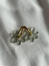 Aros colgantes plateados con dije de flor acrílica color dorado.