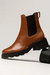 Bota Chelsea de cuero color marrón con elástico lateral negro, suela track y taco cuadrado.