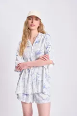 Camisa oversize de manga corta con estampado de palmeras y limones en tonos azules sobre fondo blanco. Confeccionada en lino.