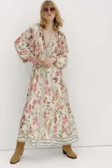 Vestido largo de viscosa con estampado floral, corte holgado, cuello redondo con botones y mangas globo largas. Incluye cinturón fino para atar.