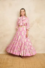 Vestido largo color rosa con estampado dorado, cuello con lazo y mangas largas.