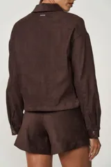 Camisa marrón de gamuza sintética, con cuello clásico, cierre frontal con botones a presión, mangas largas y dos bolsillos de parche en el pecho.