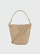 Bolso Longchamp modelo Le Roseau XS, color beige, tipo bucket bag, con correa larga ajustable para usar como bandolera.